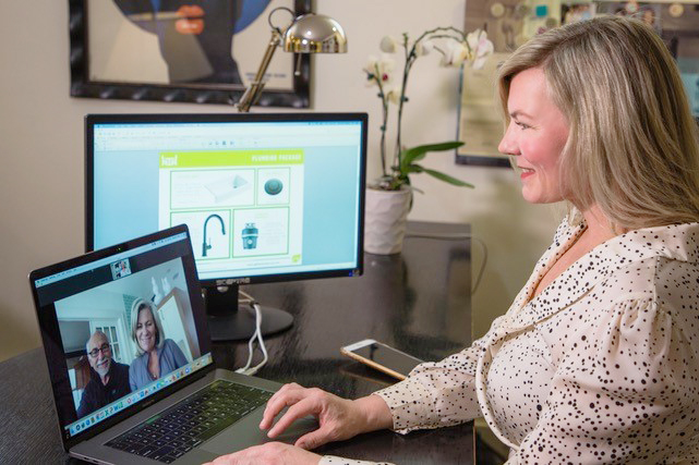 Smiling woman using computer to video chat another man and woman discussing virtual designs for a home