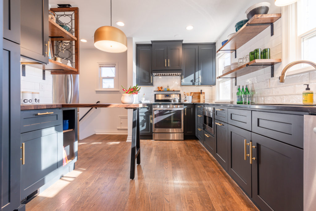 kitchen with charcoal gray cabinet and wood flooring, bright sunny light from the open windows