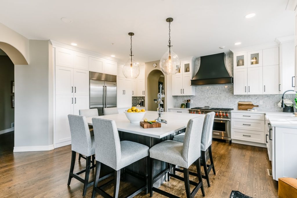 Bright kitchen with white cabinets and island with grey chairs