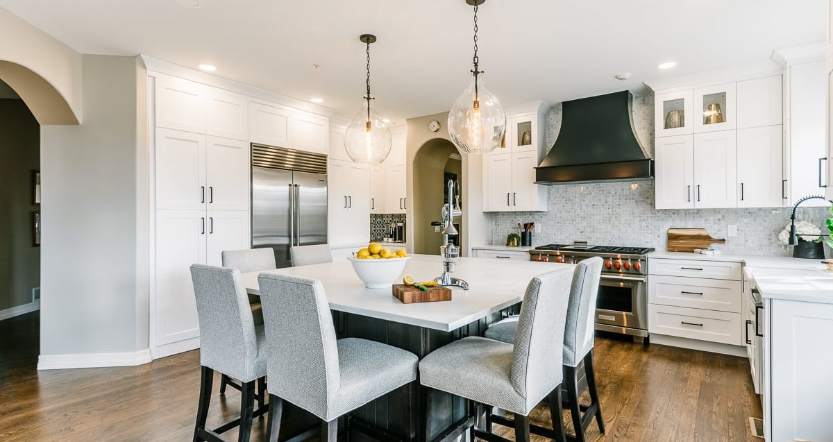 Bright kitchen with white cabinets and island with grey chairs